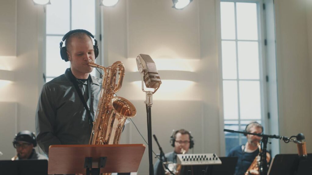 Ryan Middagh plays saxophone in a sunny studio.