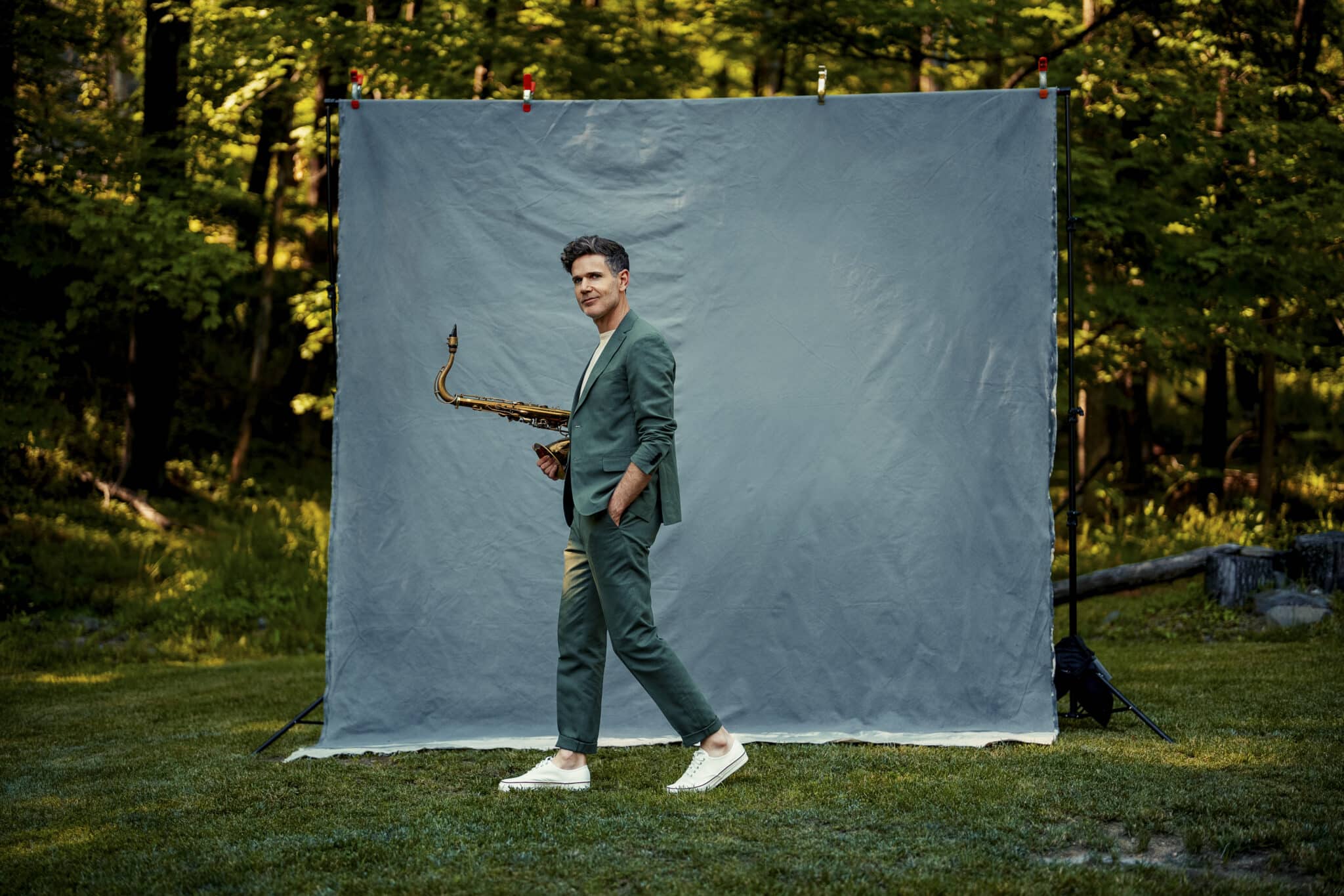 Ben Wendel stands in the middle of the frame, mid walk, saxophone tucked under his arm.