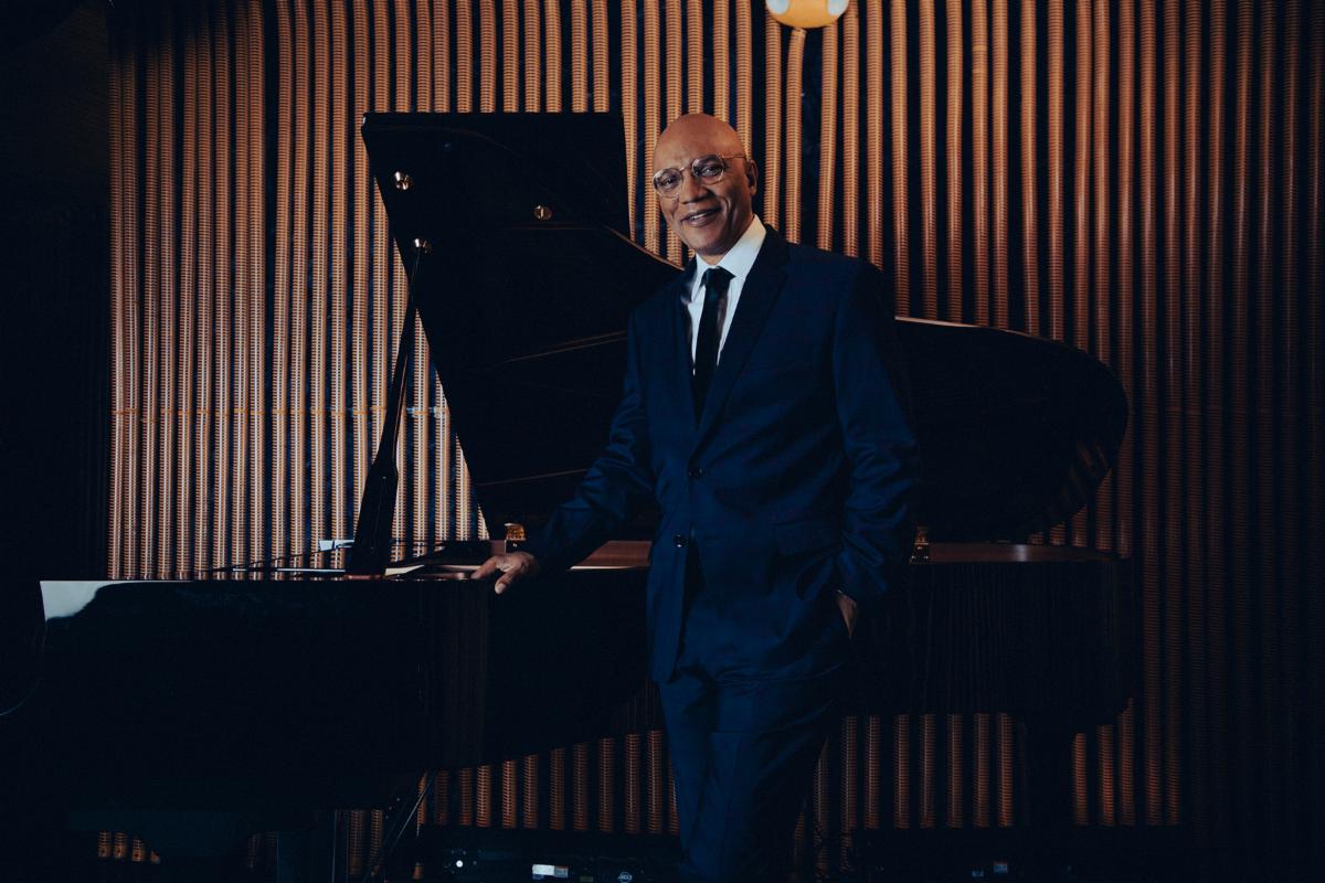 Billy Childs standing in front of a piano