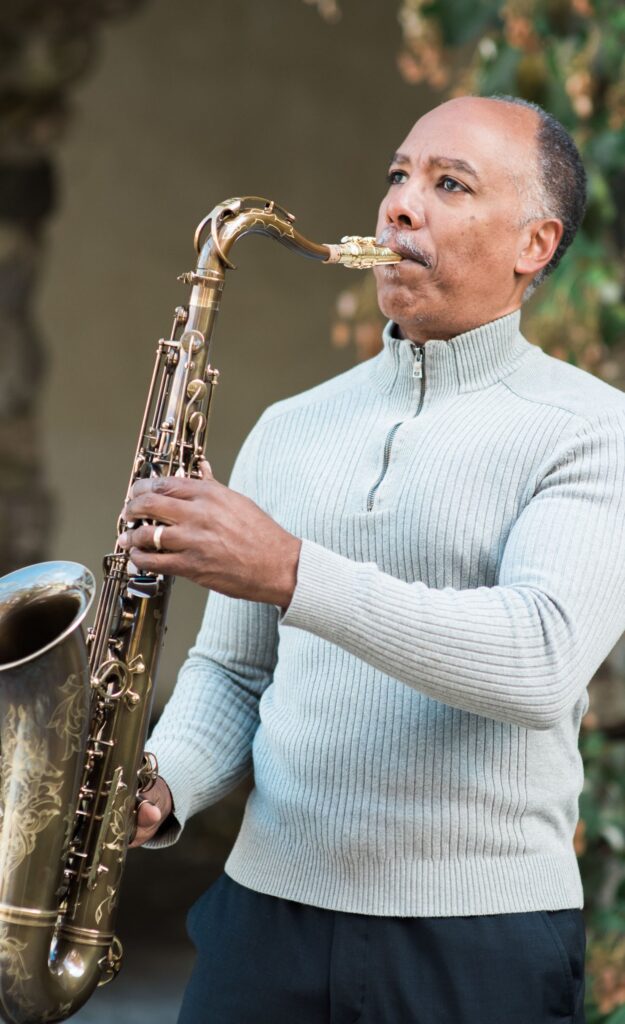 Don Braden playing the saxophone wearing a zip-up sweater. Saxophone has ornate detailing