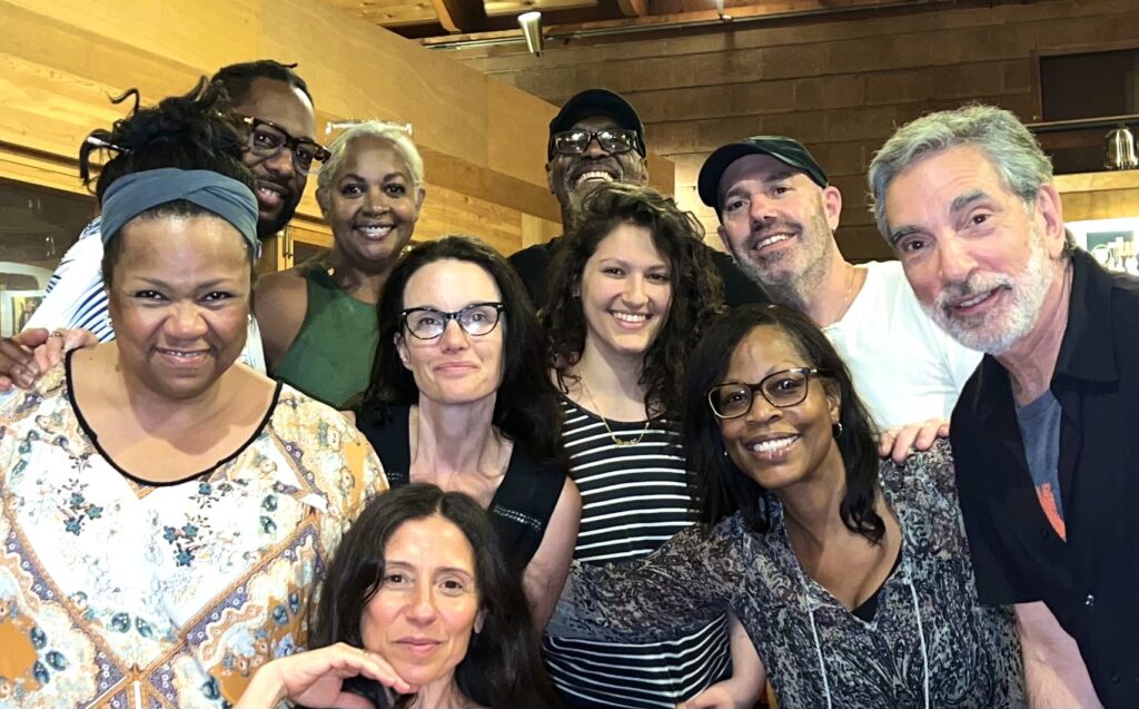 A group of 10 people stand in a group with their arms around each other, smiling at the camera. Mike LeDonne is on the far right.
