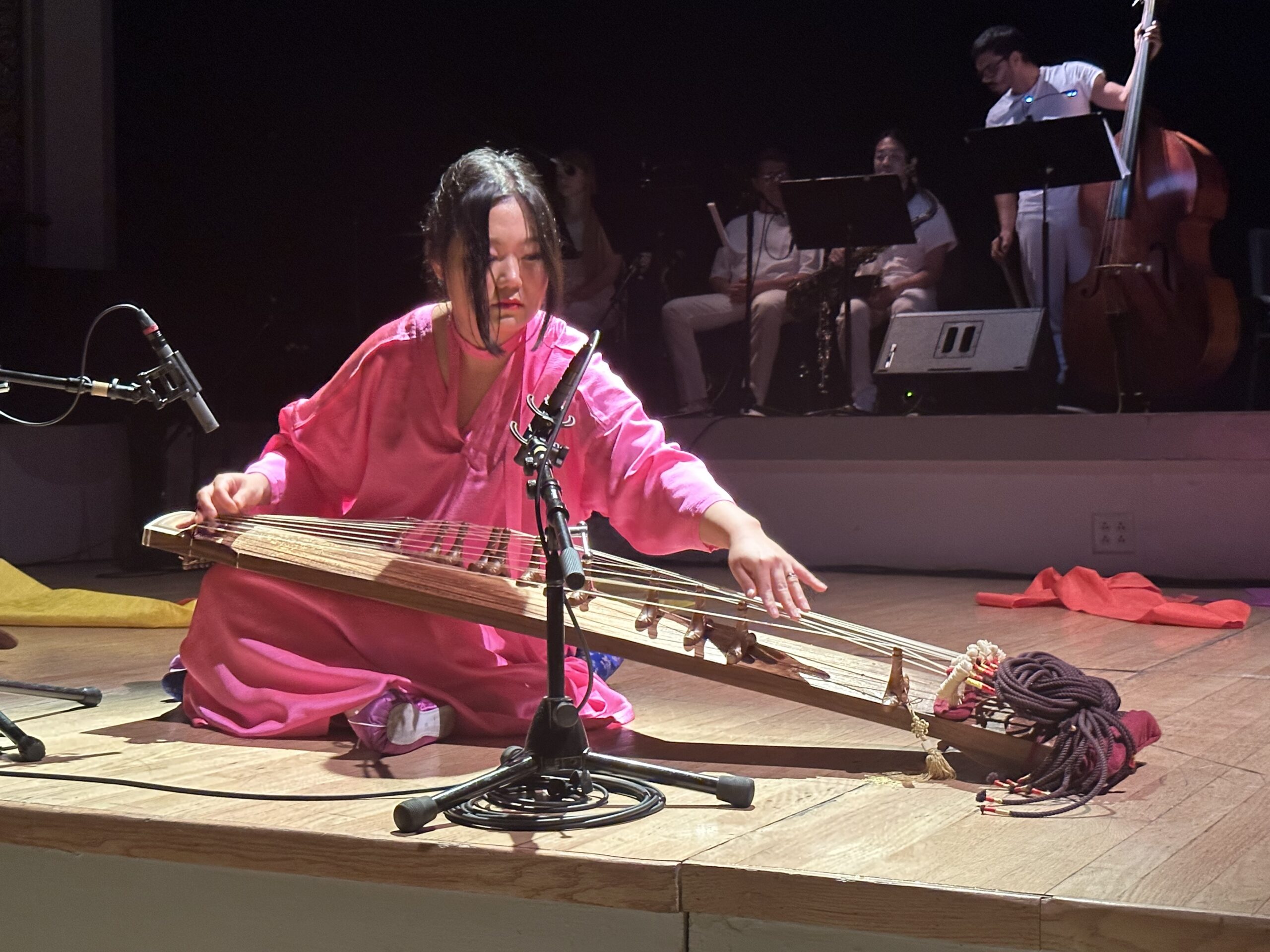 DoYeon Kim on stage wearing pink outfit and playing the gayageum