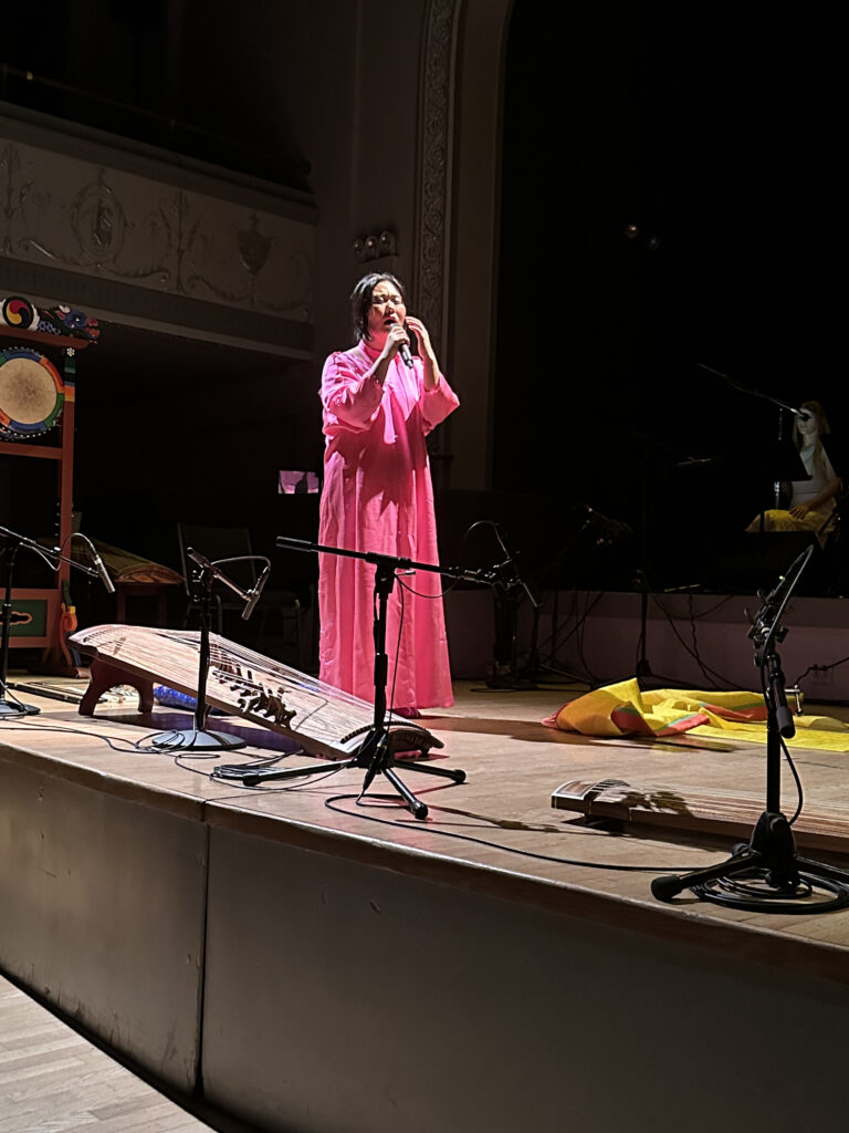 DoYeon Kim singing on stage wearing bright pink robes