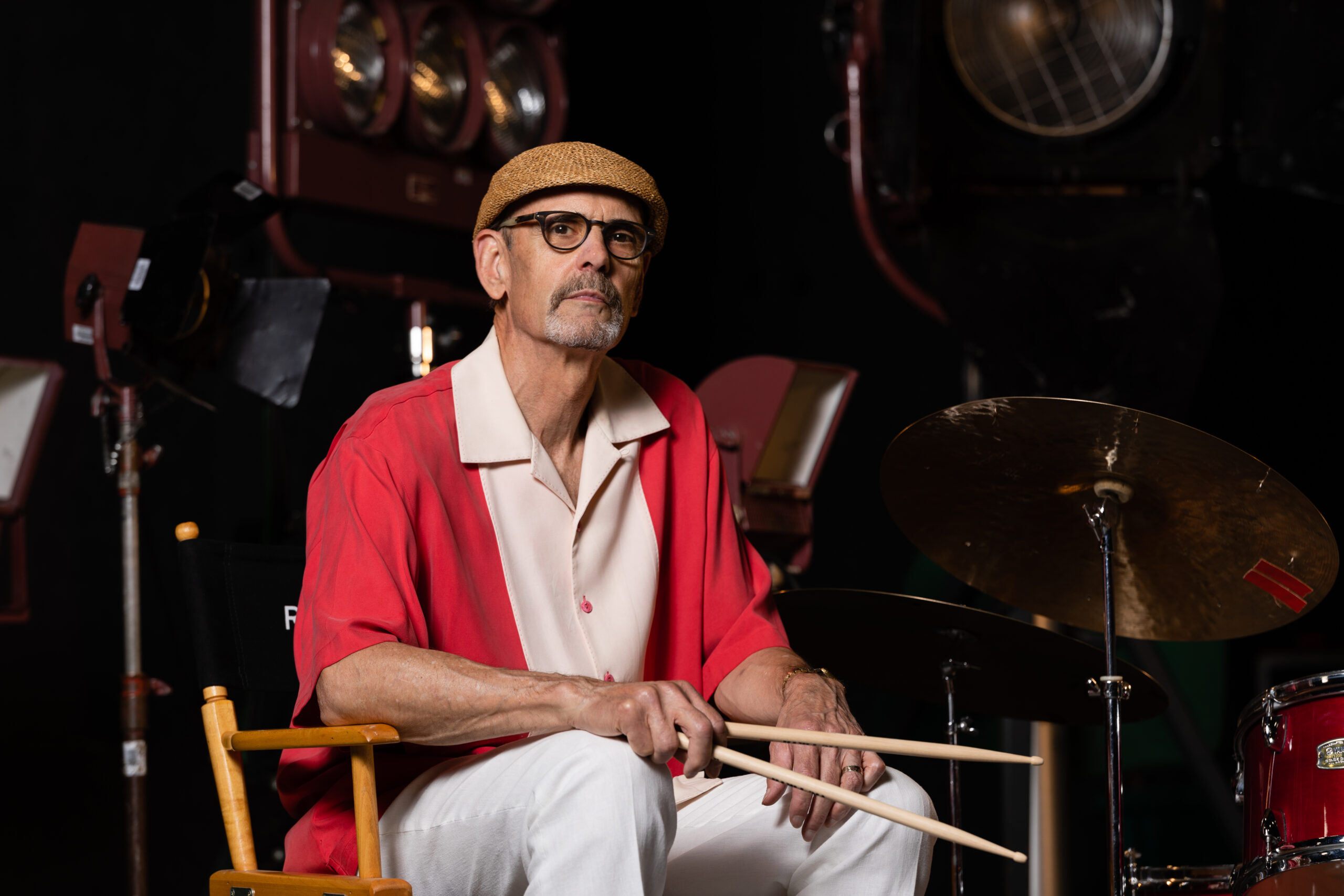 Richard Baratta wearing a red shirt holding drumsticks