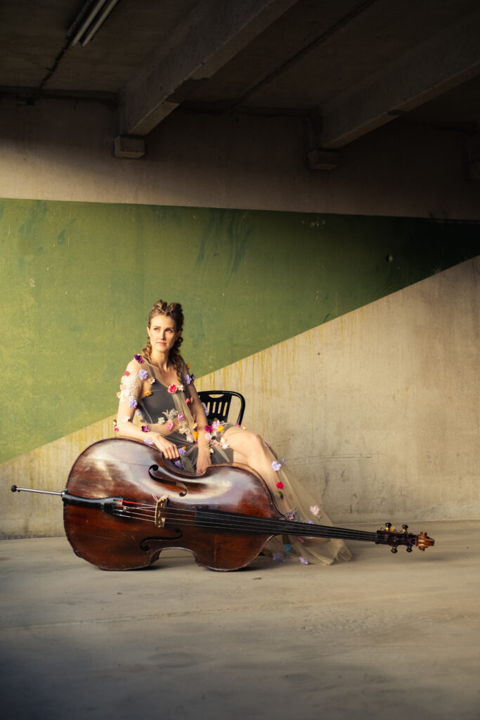 Kaisa Mäensivu sitting on chair with the upright bass lying in front of her